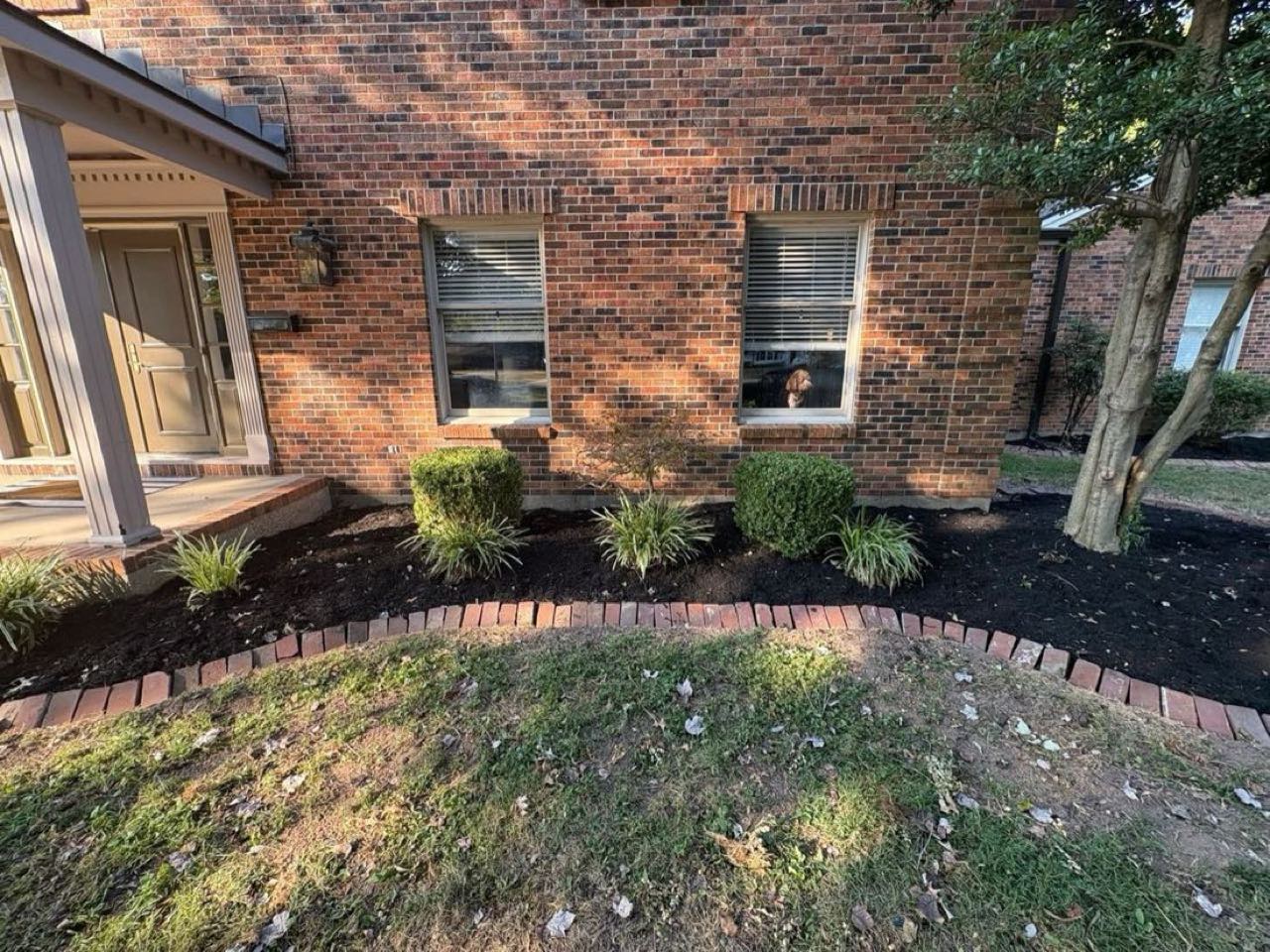 Brick-edged landscape bed along a brick home